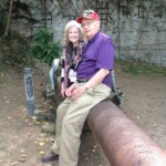 Bill Schott and Laura Leppert, President of Daughters of World War II, and Bill sitting on the remains of a cannon during the 68th Anniversary of Iwo Jima