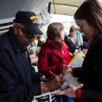 WWII veteran Ormand Knowles, signs autographs for Belgian high school students during a visit to a WWII museum in France.